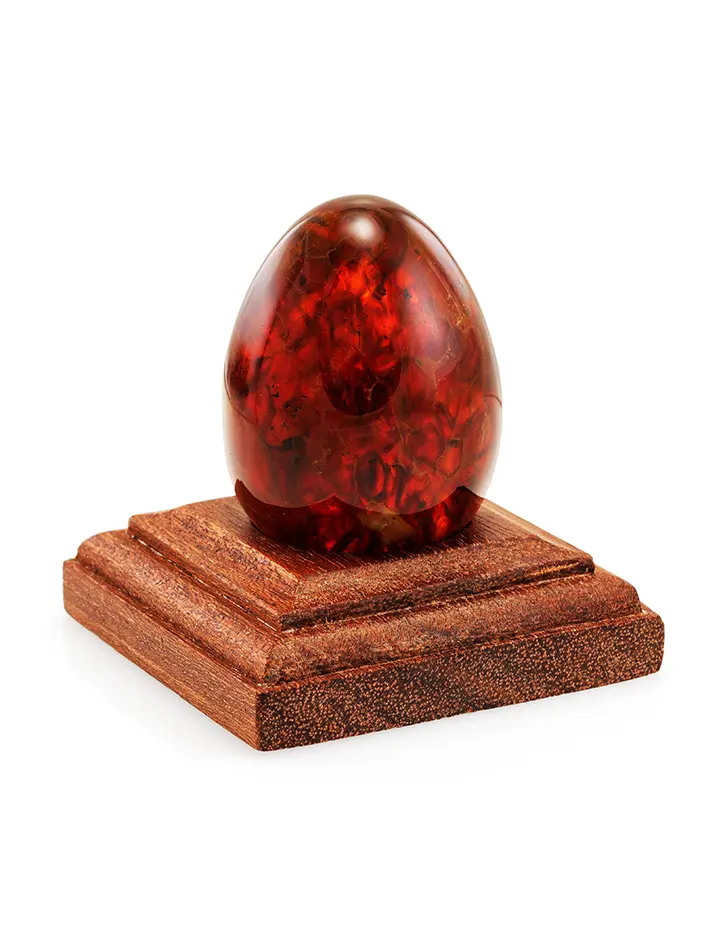 картинка Пасхальное яйцо из формованного янтаря красно-коньячного оттенка на деревянной подставке в онлайн магазине